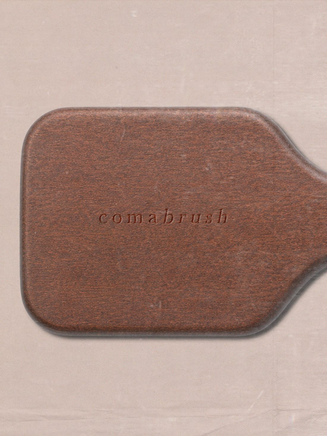 The comabrush wordmark debossed into the back of the walnut paddle