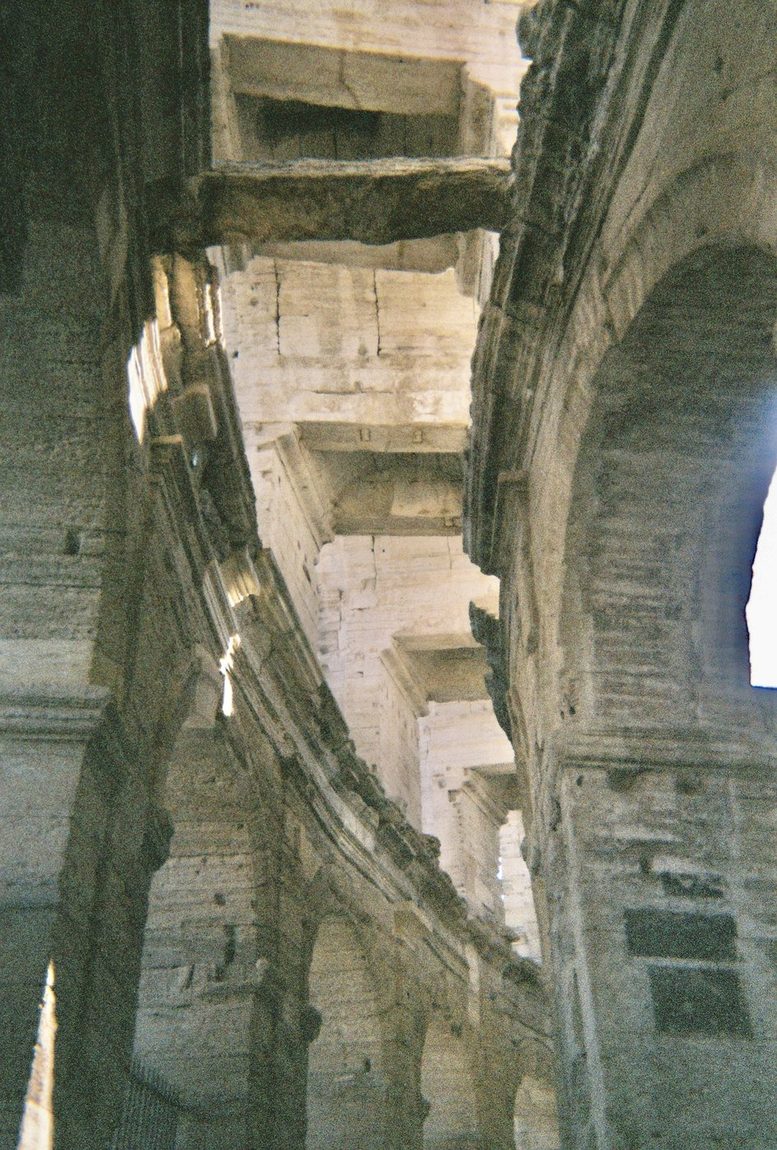 Looking up through the tiered stone arches of a Roman amphitheatre
