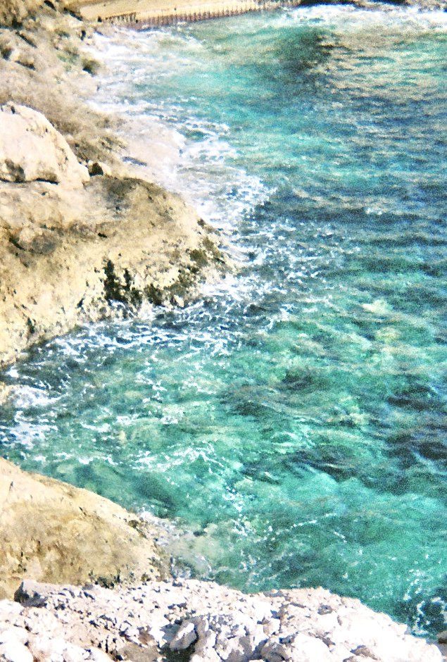 Pale rock shelving into clear turquoise water along a rocky coast