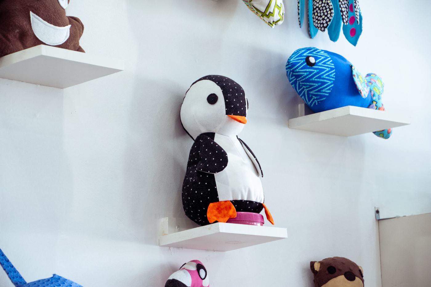 A handmade felt penguin on a white shelf