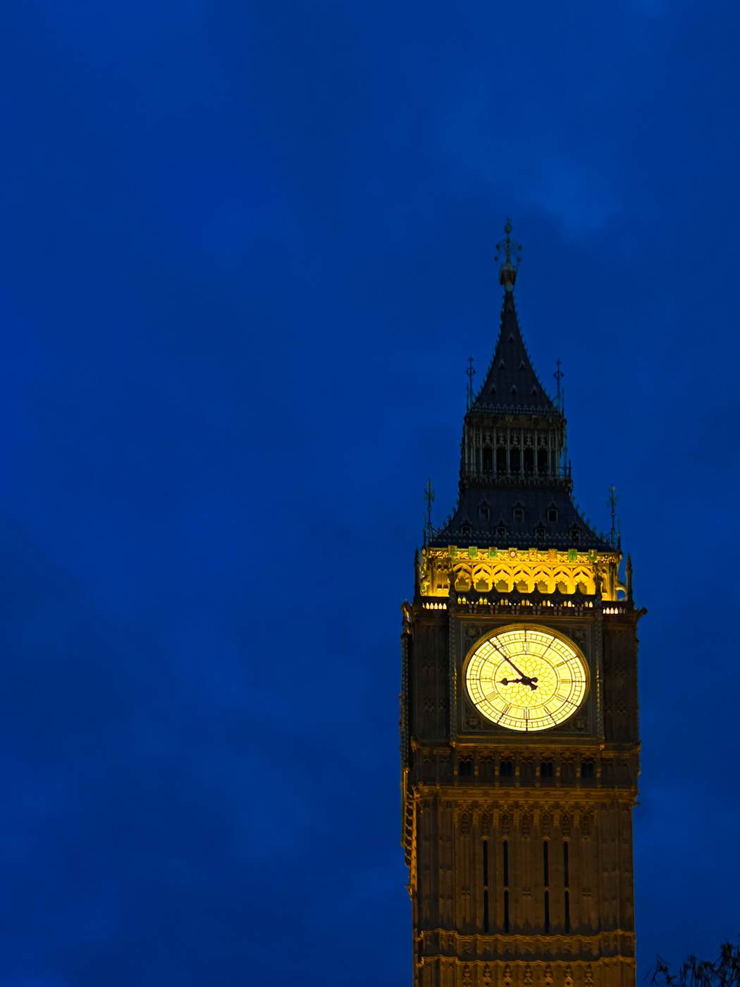 The lit clock face of Big Ben against a deep blue evening sky